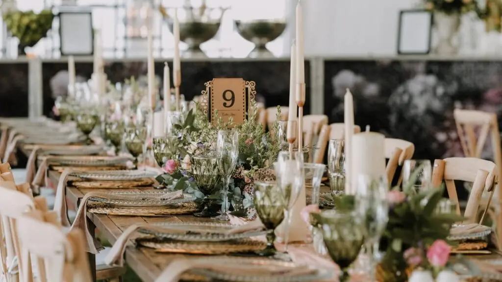 Tavola allestita per un matrimonio con colori verde bottigna e beige e calici a tono con decorazioni